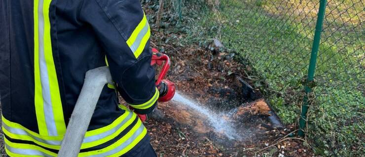 Hilflose Person und Baumstumpf brennt. Feuerwehr hilft